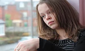 Sad teenage girl looking out of a window