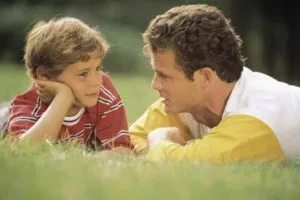 father looking at his son lying down in the field