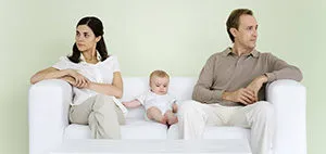 couple with child sitting on a sofa and looking the opposite way