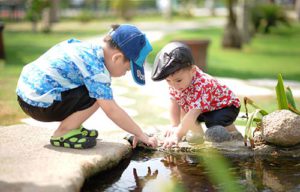 niños agachados tocando el estanque de agua